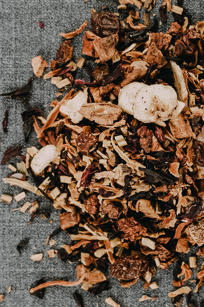 Bananen, Erdbeeren und viele Nelken verstreut auf grauem Untergrund