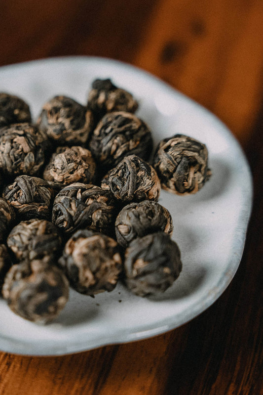 1 cm dick zusammengerollte Schwarzteeblätter aus Yunnan auf Holztisch