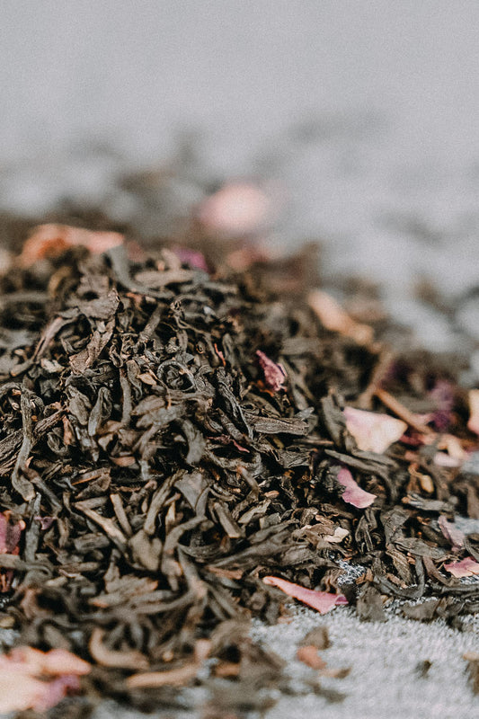 Rosenblüten auf schwarzem Tee